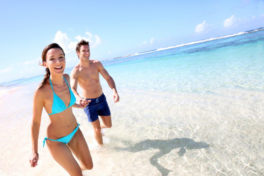 Young man and women in bathing suits running on the beach