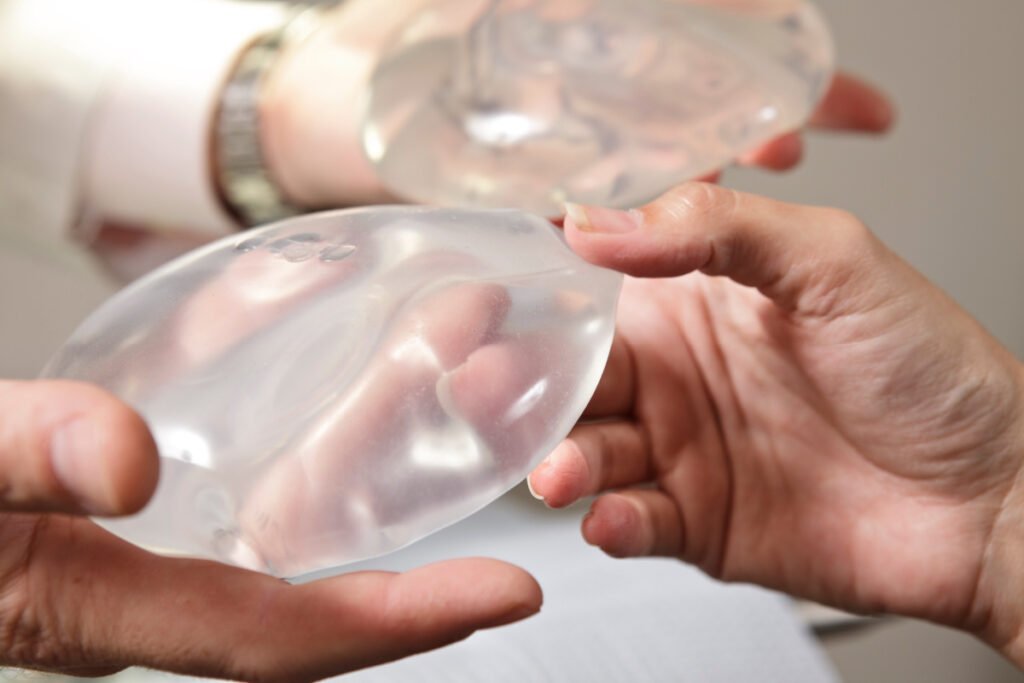 Woman holding different types of breast implants at a breast augmentation consultation