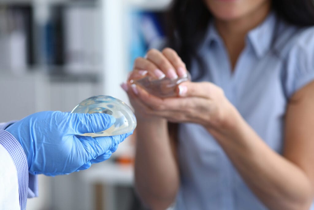 Woman holding breast implant sizers during a consultation with a breast augmentation surgeon
